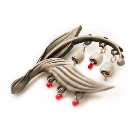 A dynamic side view of the Sacred Blood pin, the beads resting on a white background.