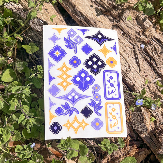A single sheet of Speedwell Art Stickers photographed against the vibrant green and indigo of living Speedwell flowers.