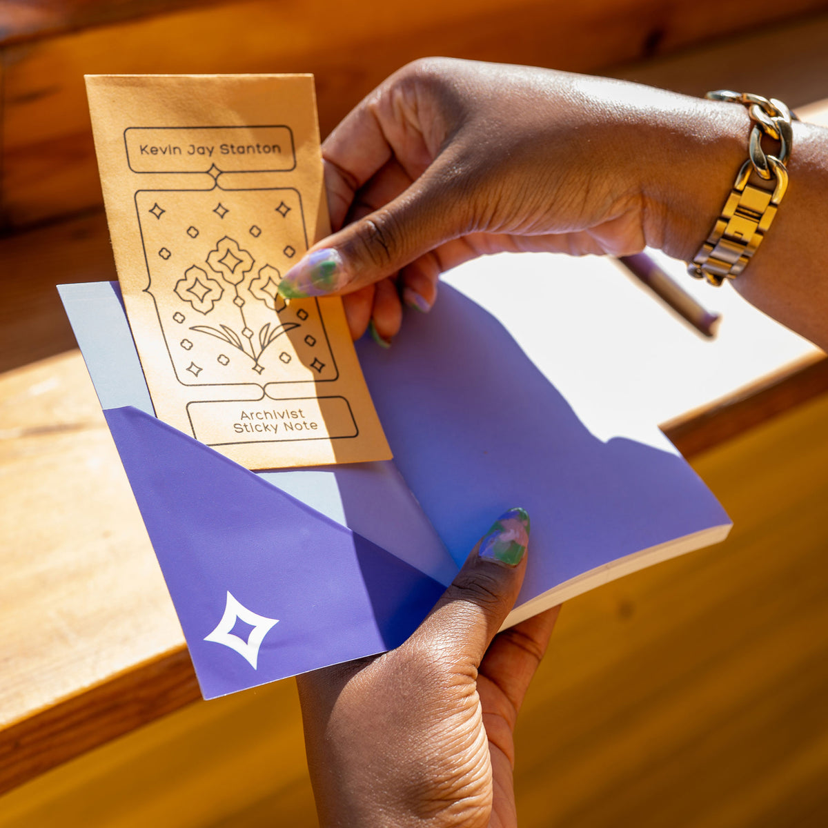 A close-up of hands pulling the Archivist Sticky Note envelope out of the pocket made from the Diamond Pocket Sticker.