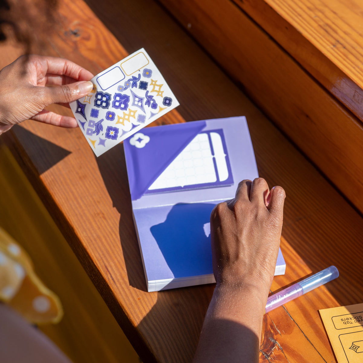 A person shows off the Speedwell Art Stickers against the Calendar Sticky Note nestled inside the pocket made from the Flower Pocket Sticker.