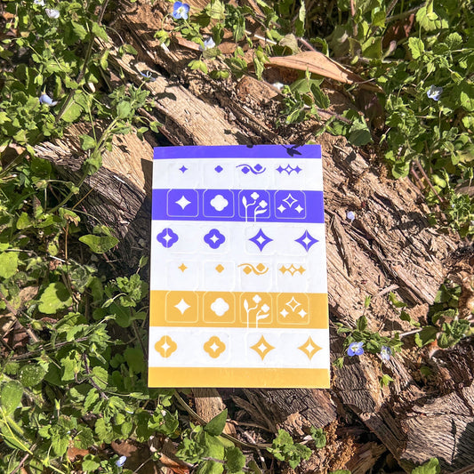 A single sheet of Speedwell Tab Divider Stickers photographed against the vibrant green and indigo of living Speedwell flowers.