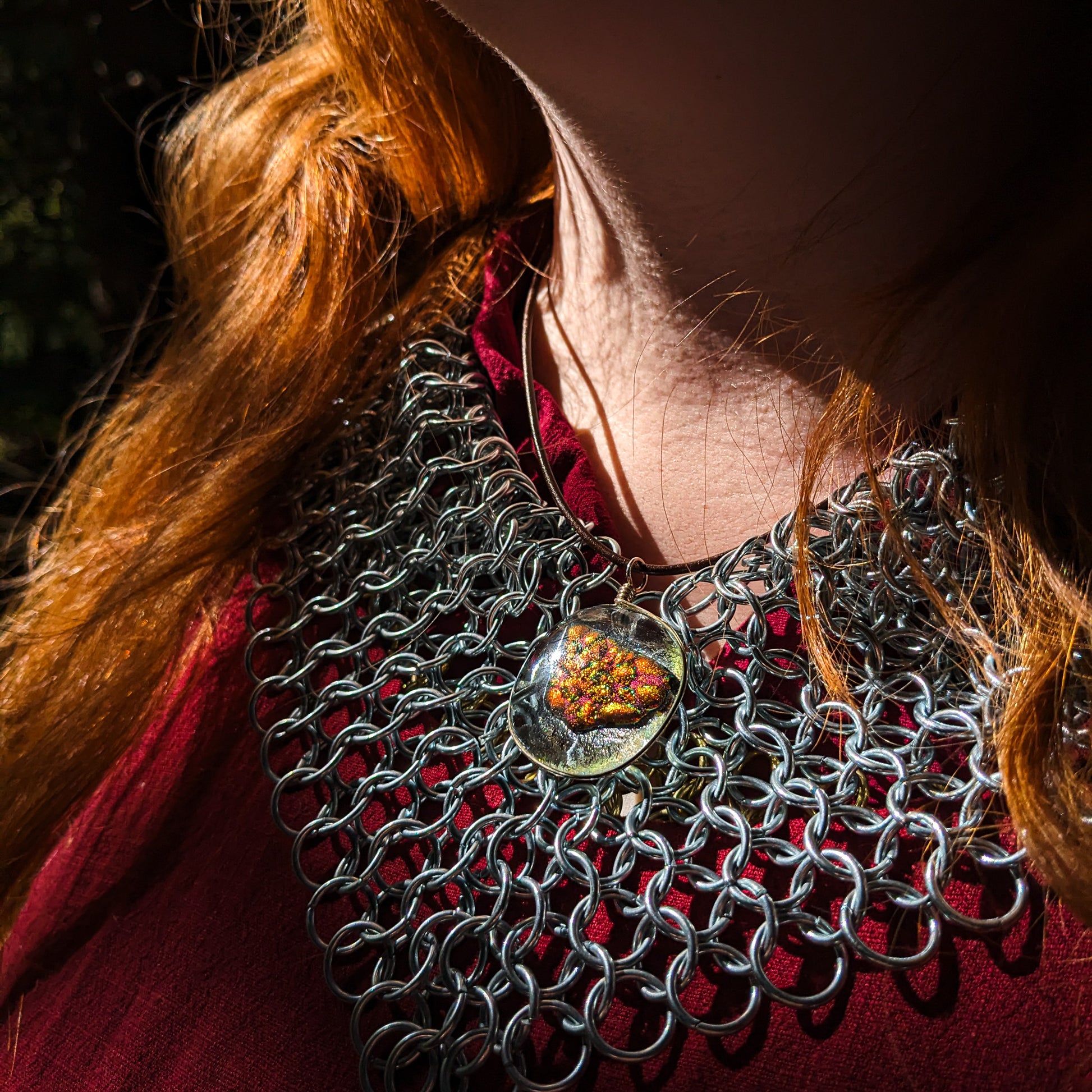 close-up of a model in chainmail wearing the ember glass pendant.