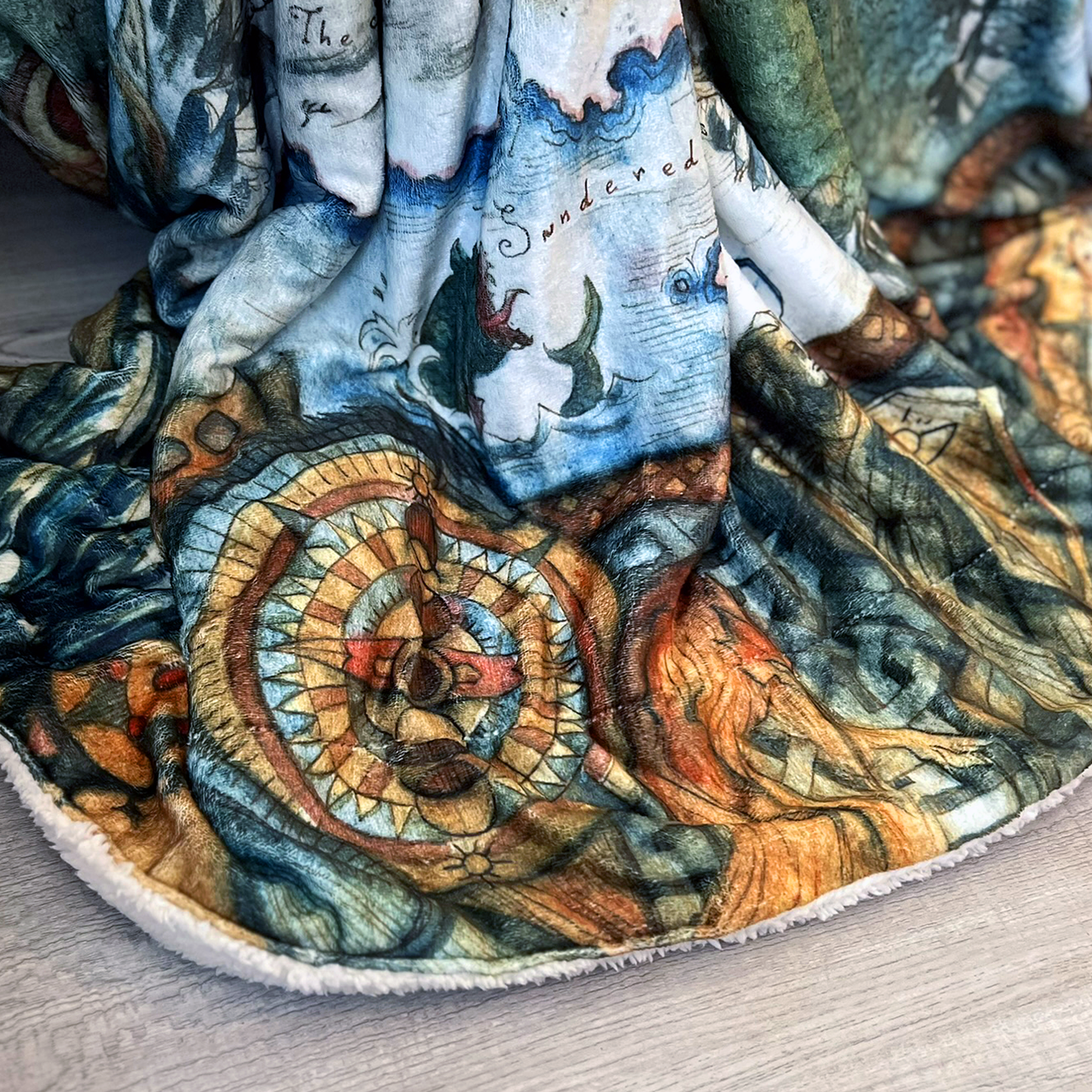 A closeup of the Thedas Map Blanket, focused on the Sundered Sea and the compass rose. This part of the blanket is pooling on the floor.
