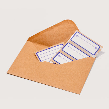 An array of white and indigo Nameplate Stickers peeking out of a brown kraft envelope on a white background.