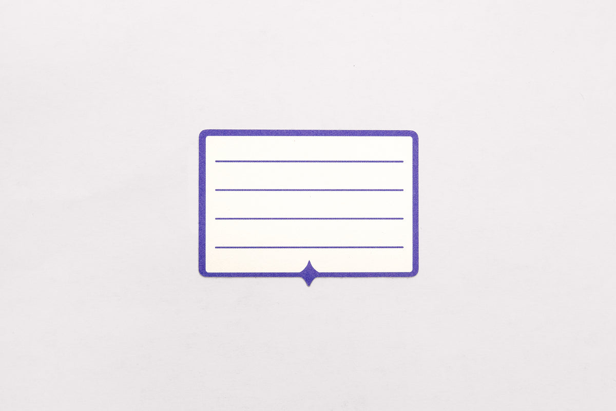 A white and indigo paper label sticker with multiple lines for written text pictured on a white background.