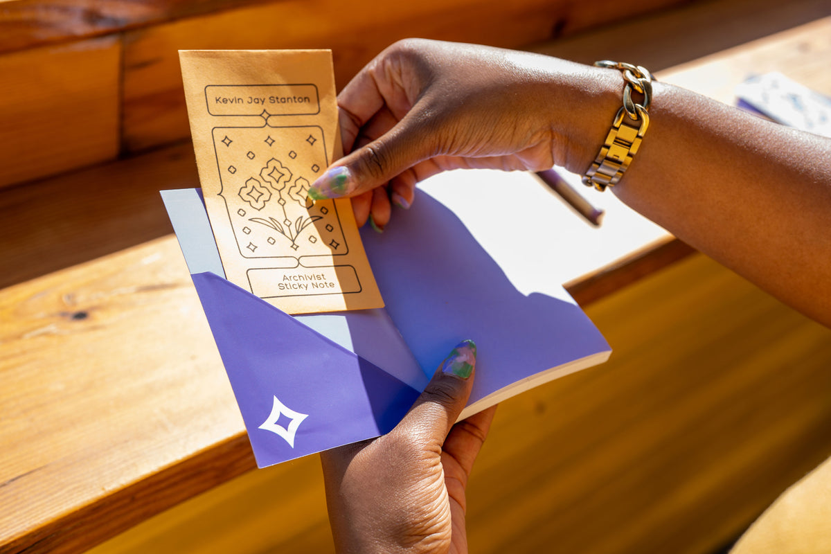 A close-up of hands pulling the Archivist Sticky Note envelope out of the pocket made from the Diamond Pocket Sticker. 