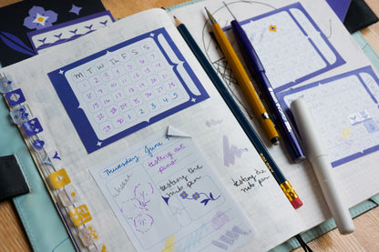 A styled flat-lay of a bullet journal or planner spread featuring decorated Calendar and Archivist sticky notes.