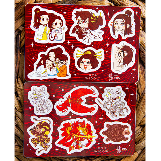 Iron Widow: Trio Sticker Sheet and Iron Widow: Mecha Sticker Sheet resting together on a warm brown wicker background.