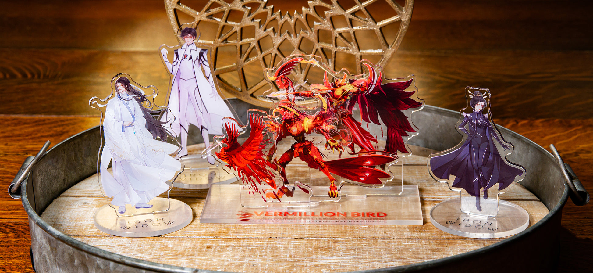 All Iron Widow acrylic standees on tin and wooden table centerpiece and gold decoration in background.