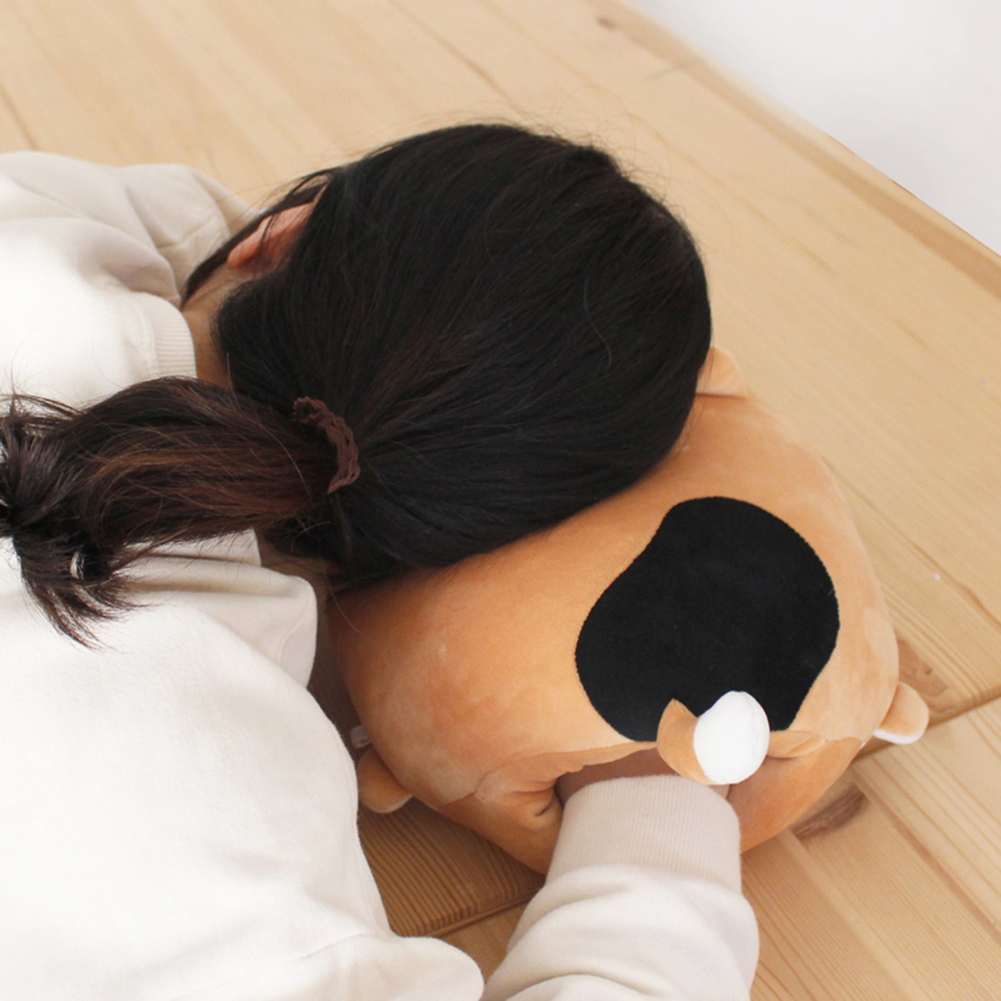 Model rests prone with head on calico cat cushion and right hand inside of cushion.